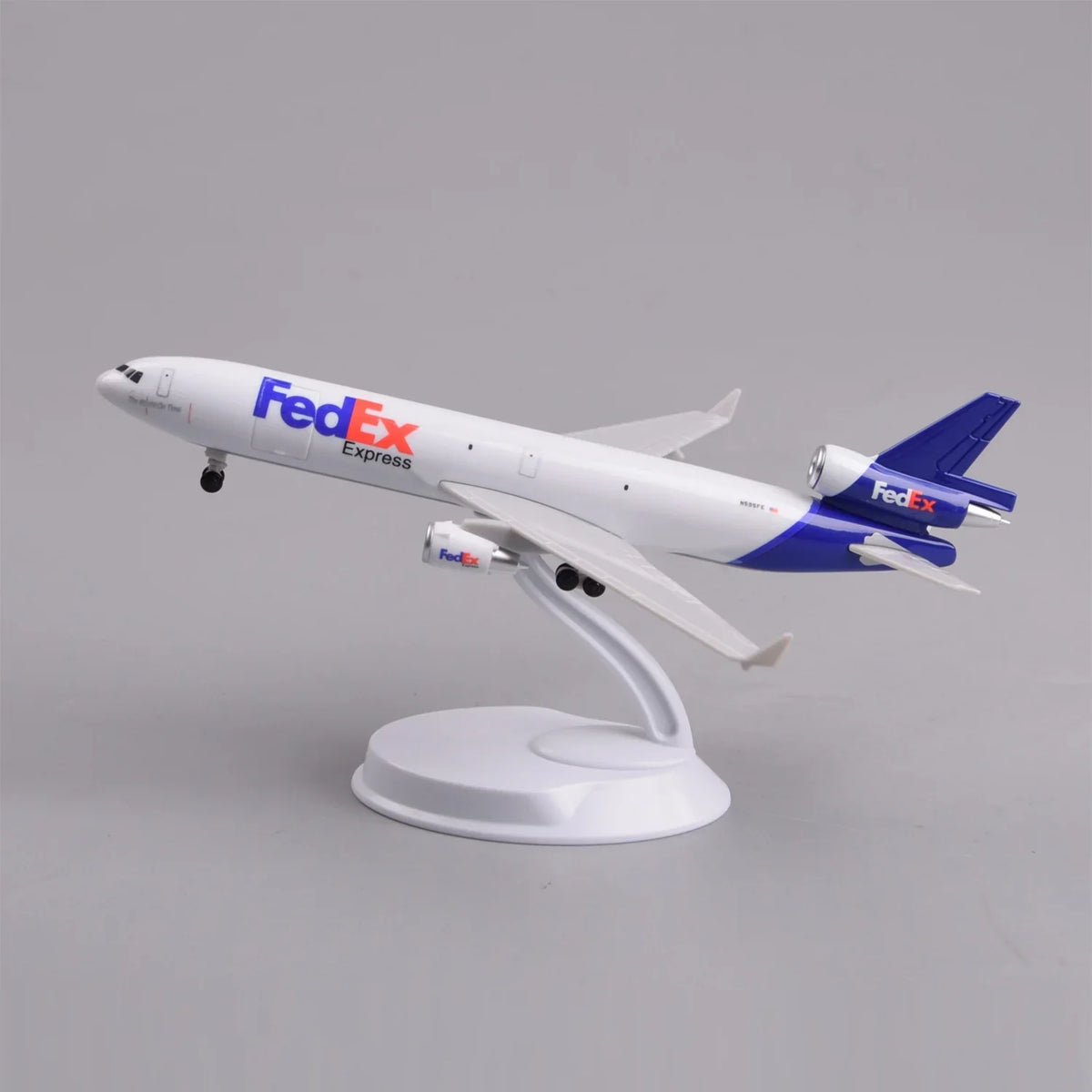 FedEx MD-11 cargo jet model in a climbing takeoff pose on its display stand, side view